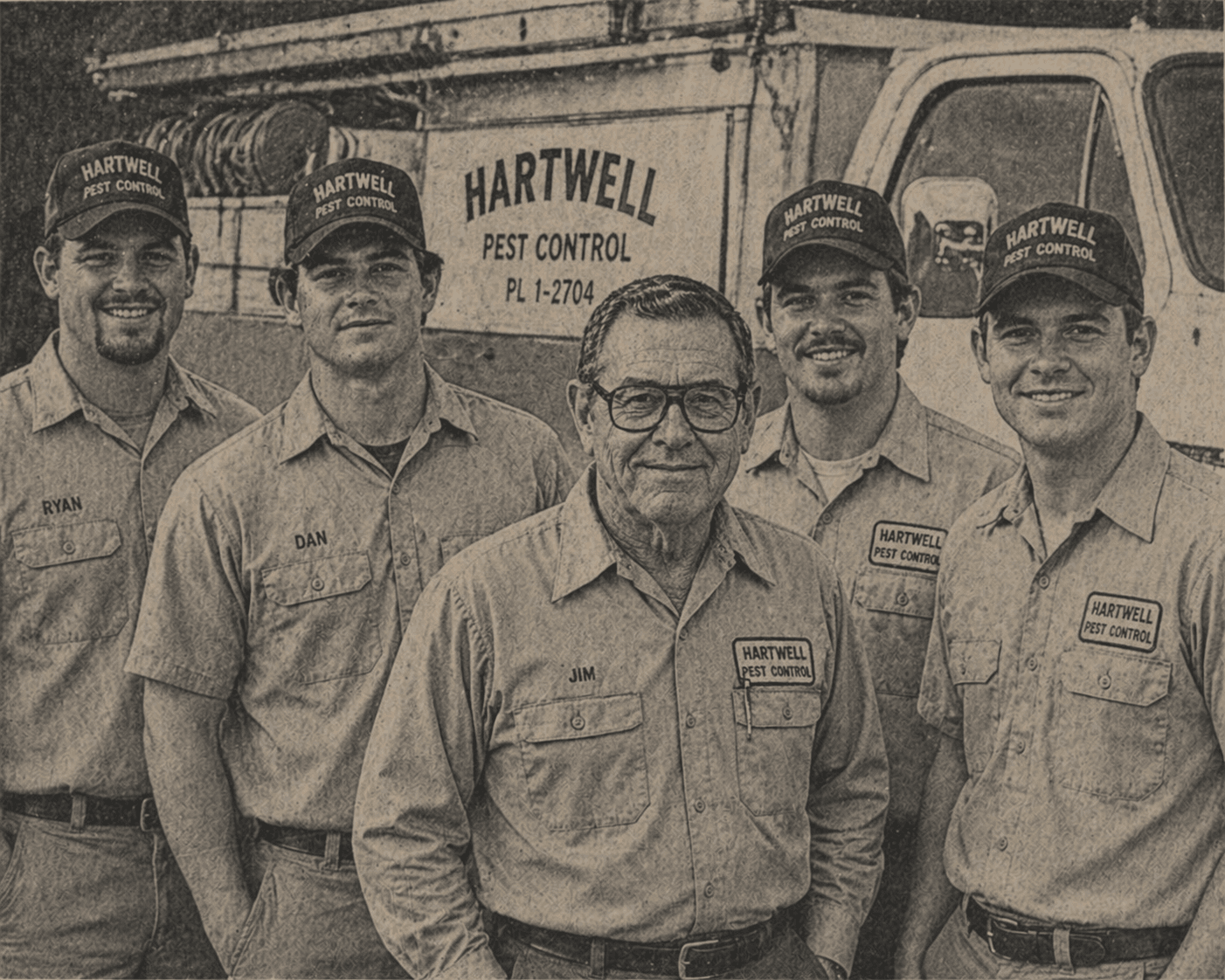 Five men in matching Hartwell Pest Control uniforms standing in front of a company truck. Jim is at center.
